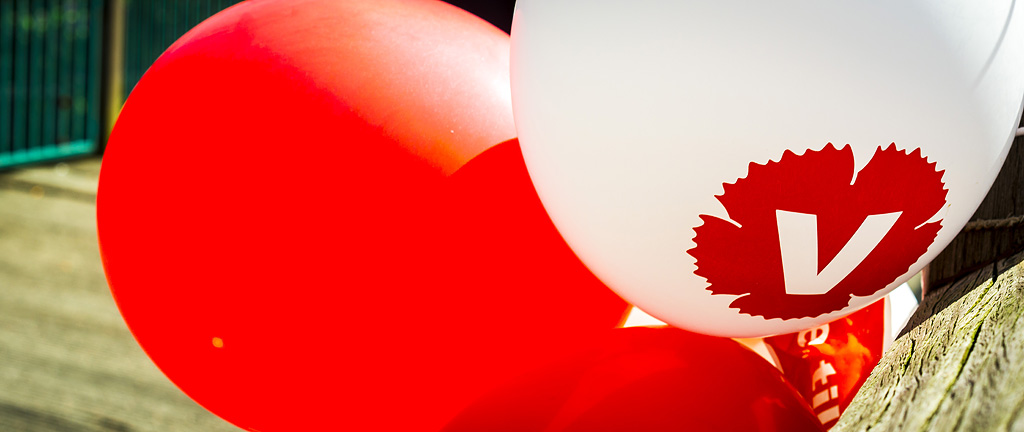 närbild av ballonger. En ballong har Vänsterpartiets logga tryckt på.