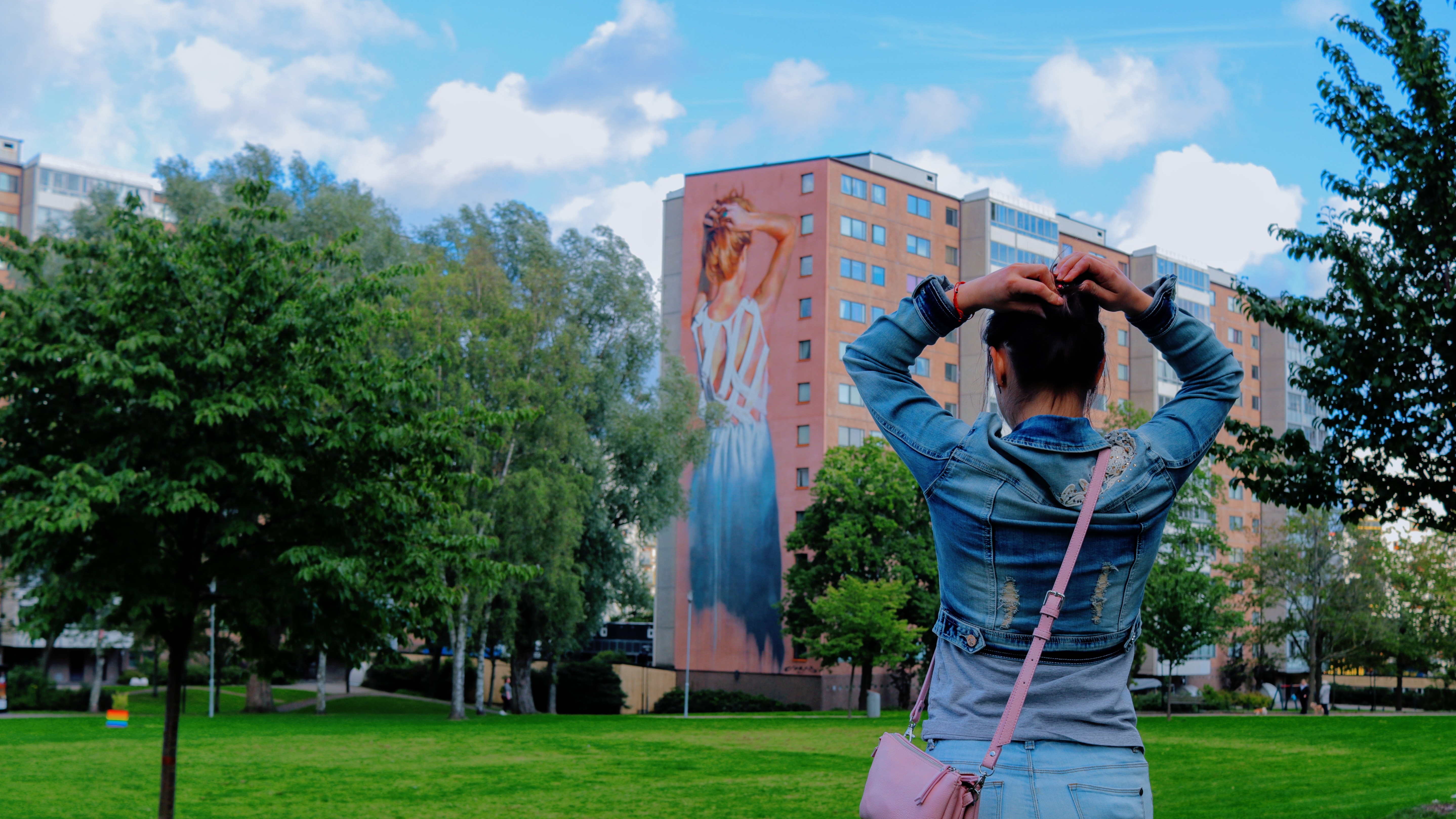 Kvinna står i Positivparken i Frölunda och sätter upp håret i en knut.