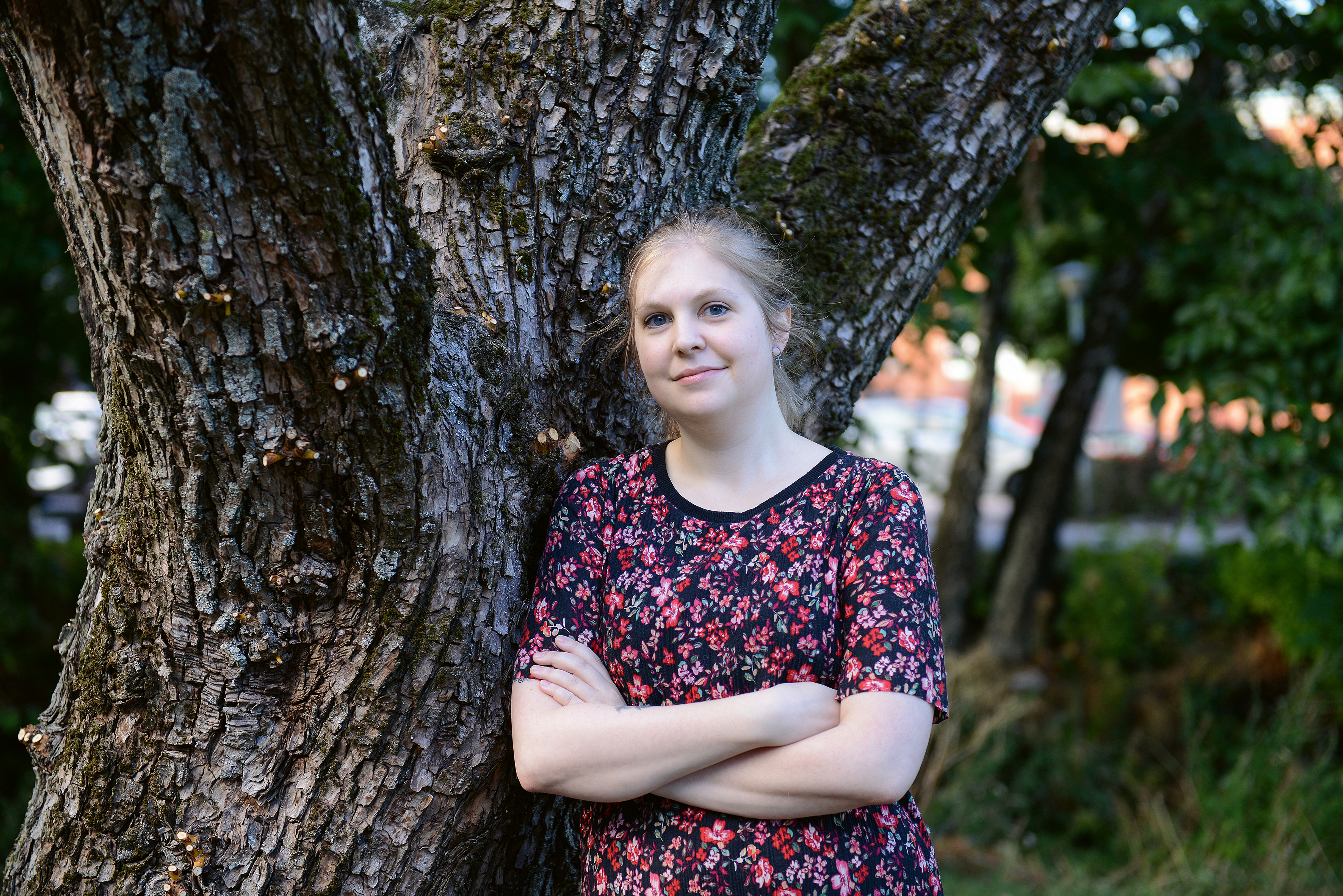Karin Karlsson med armarna i kors lutad mot ett träd
