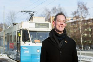 Håkan Eriksson står vid spårvagnshållplats. Bakom skymtar en spårvagn.