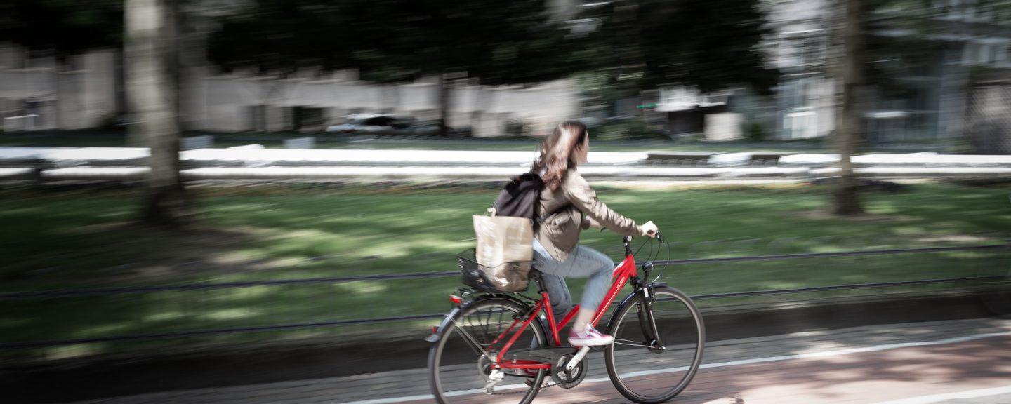 Kvinna cyklar på röd cykel i stadsmiljö