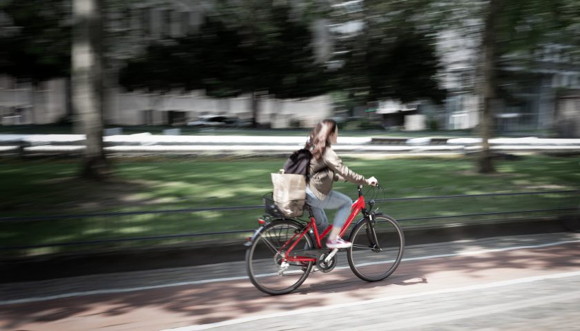 Kvinna cyklar på röd cykel i stadsmiljö